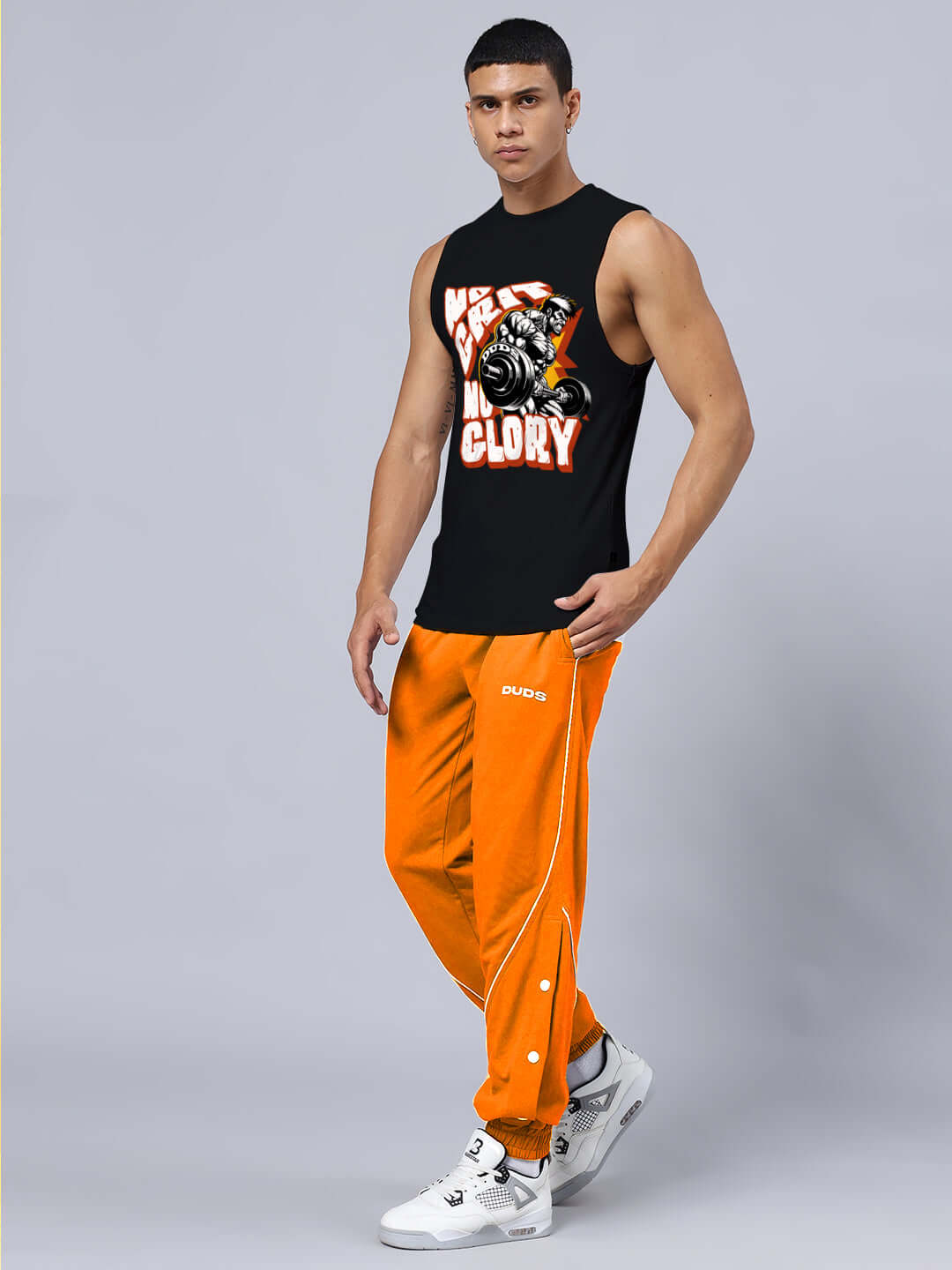 Unisex relaxed fit gym co-ord set featuring black sleeveless top with 'No Grit No Glory' print and orange joggers with elastic waistband.