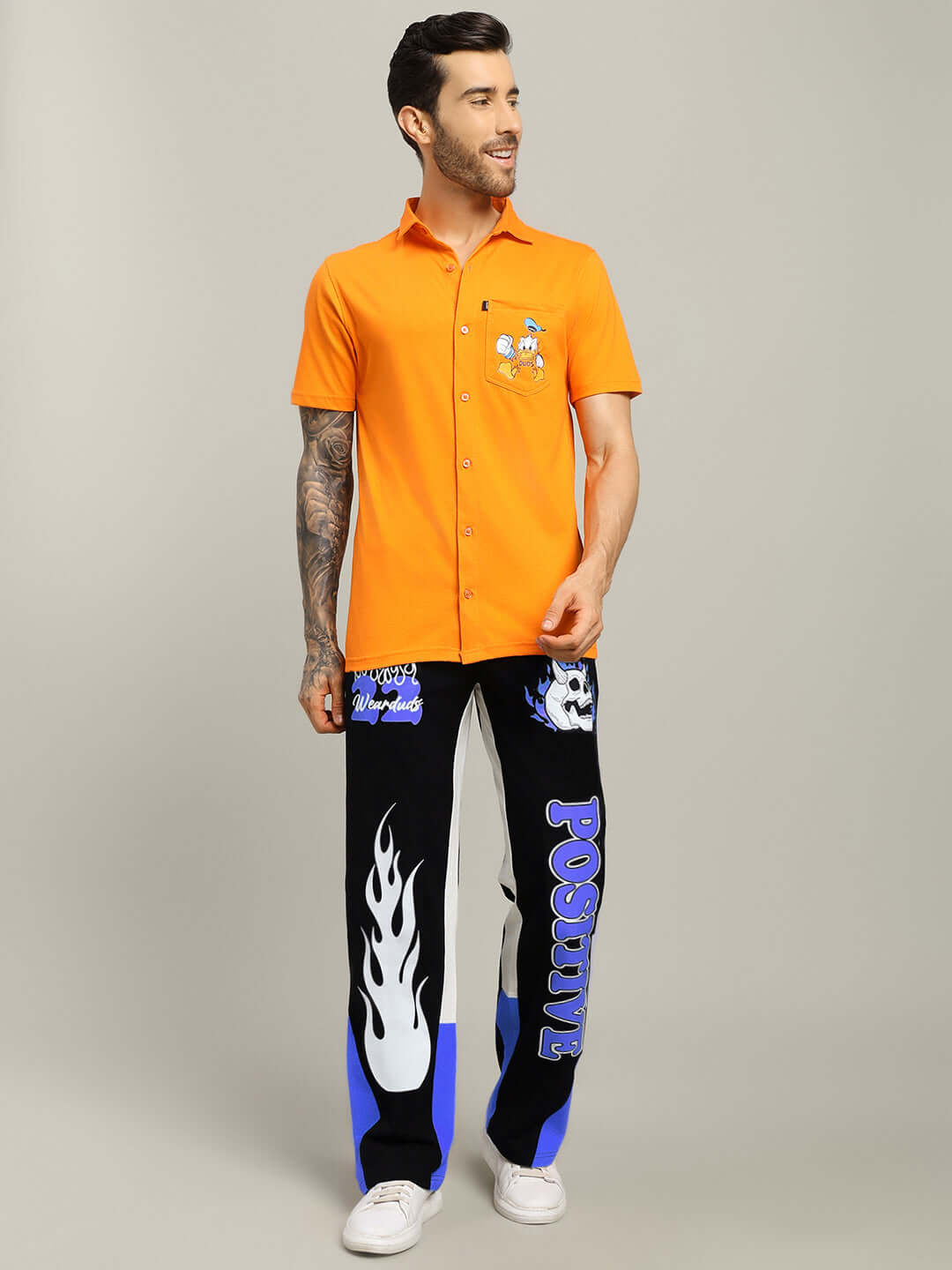 Model wearing FEARLESS CONTRAST POSITIVE RELAXED FIT JOGGERS in black-blue with flame design, paired with orange shirt.