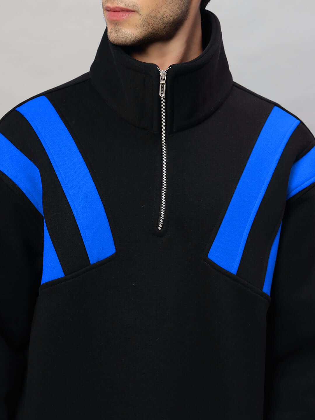 Person wearing a black fleece jacket with blue colorblock design and zipper closure.