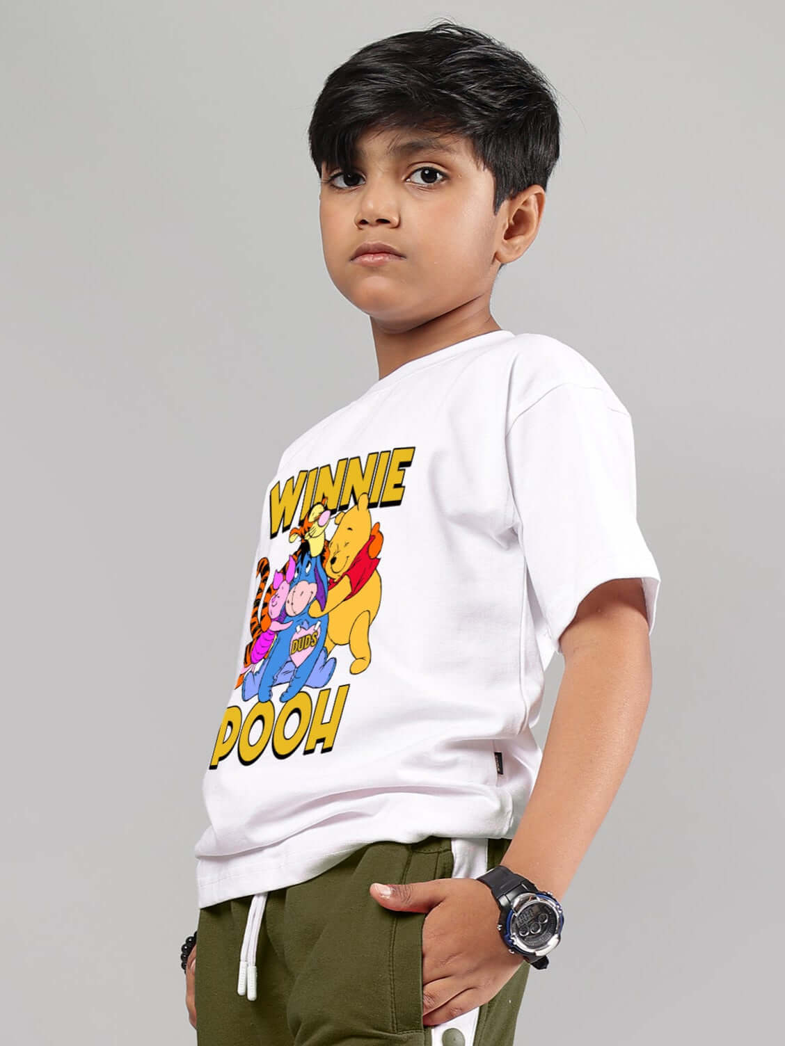 Child wearing a white unisex Winnie the Pooh T-shirt by DUDS, designed for boys and girls, showcasing colorful characters on the front.