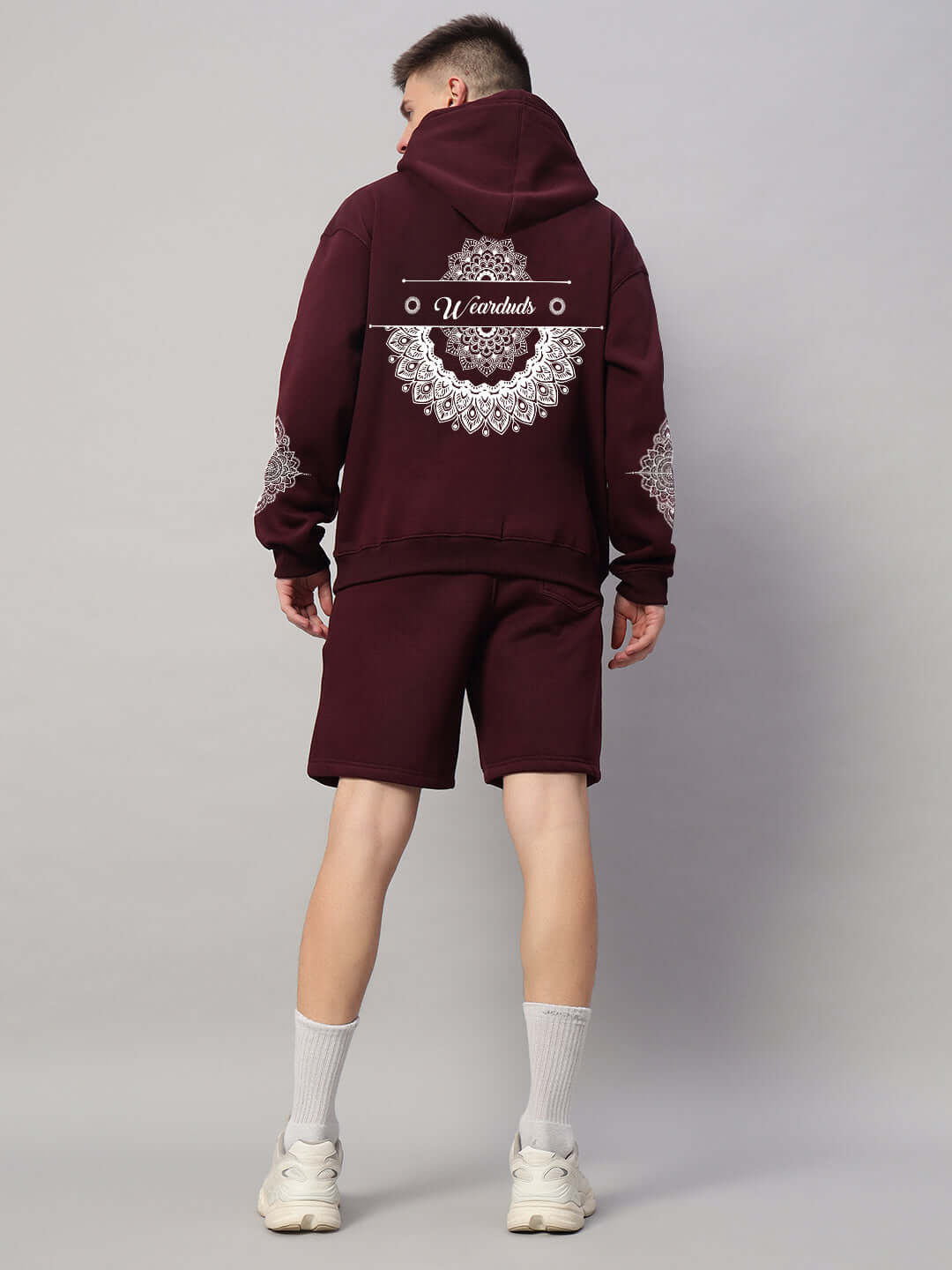 Back view of a man wearing a wine-colored Yantra fleece co-ord set with intricate patterns, featuring a hoodie and shorts.