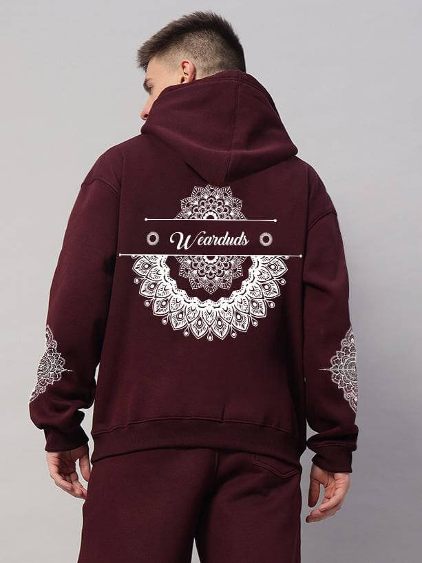Man wearing Yantra Fleece Hoodie in wine color with intricate mandala designs on the back and sleeves.