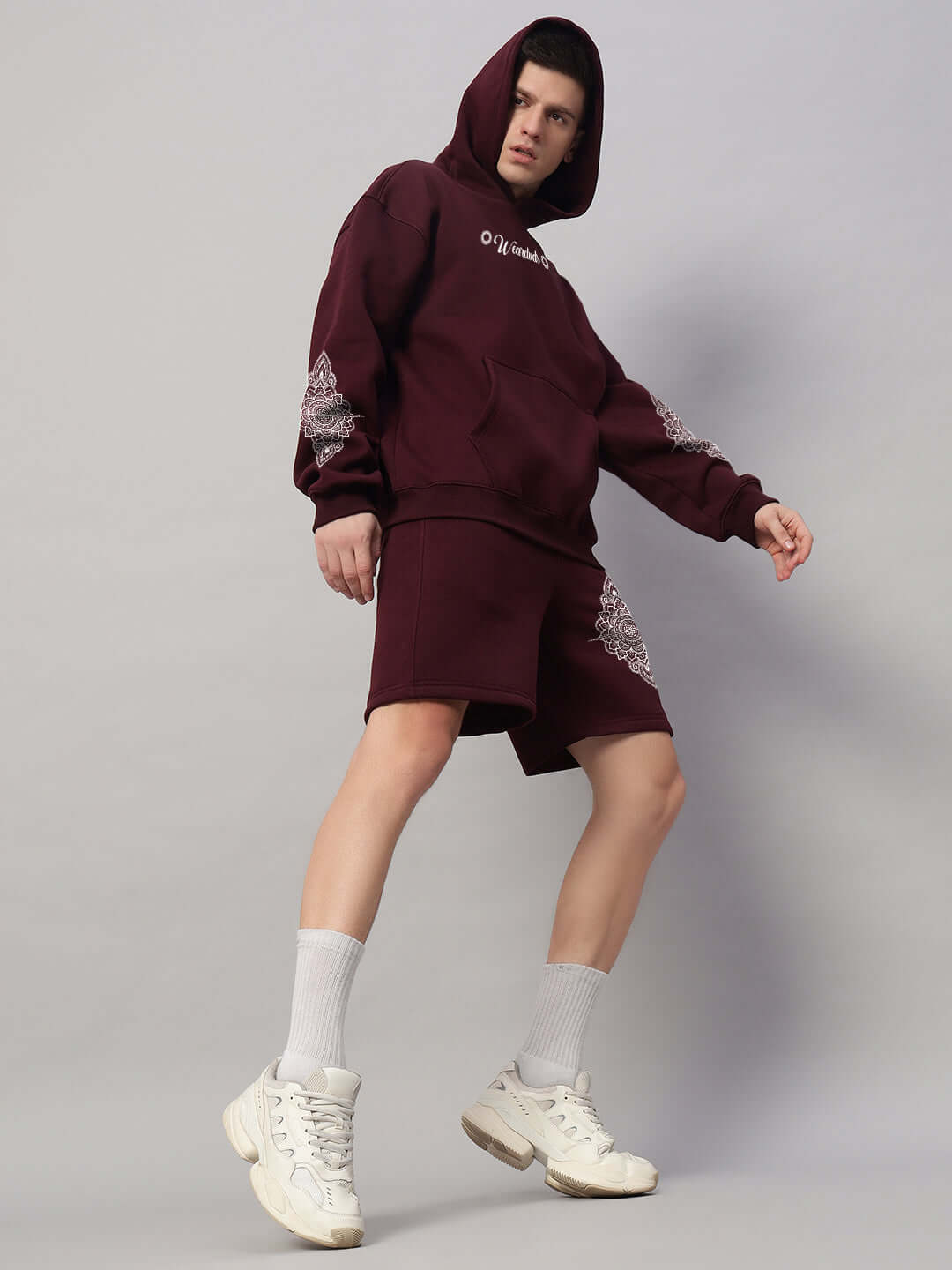 Model wearing Yantra Fleece Hoodie in wine color, showcasing streetwear style with matching shorts and white sneakers.