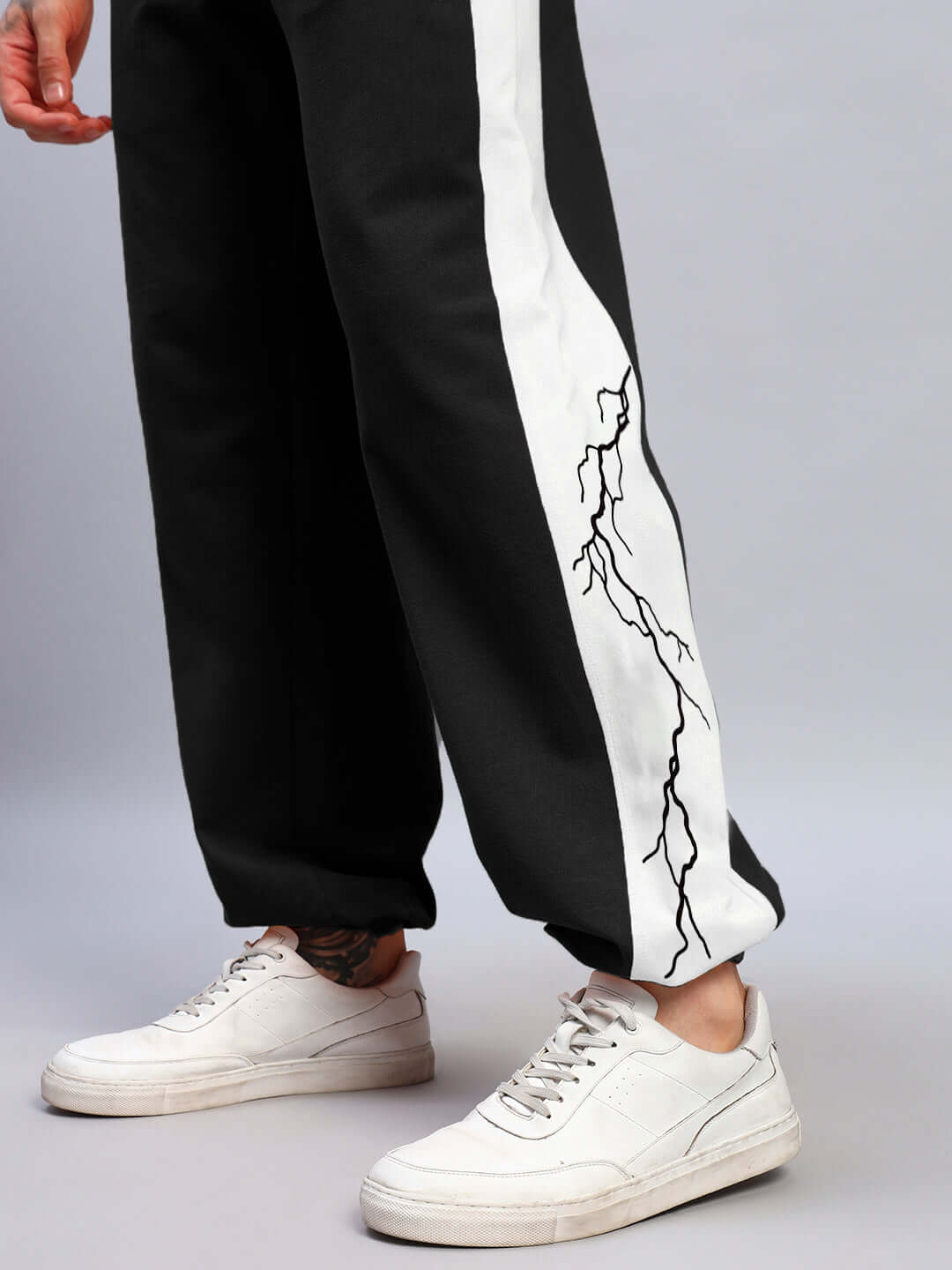 Black and white relaxed fit joggers with lightning bolt design, worn with white sneakers.