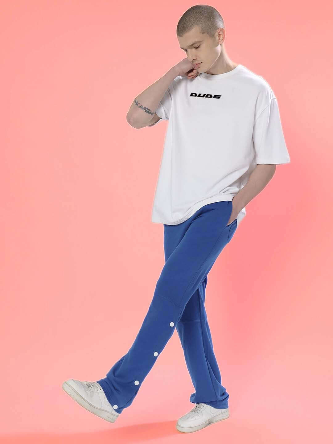 Model wearing THINK HIGHER OVER-SIZED T-SHIRT WHITE made from premium heavy gauge fabric, 97% cotton French terry, 3% elastane, on pink background.