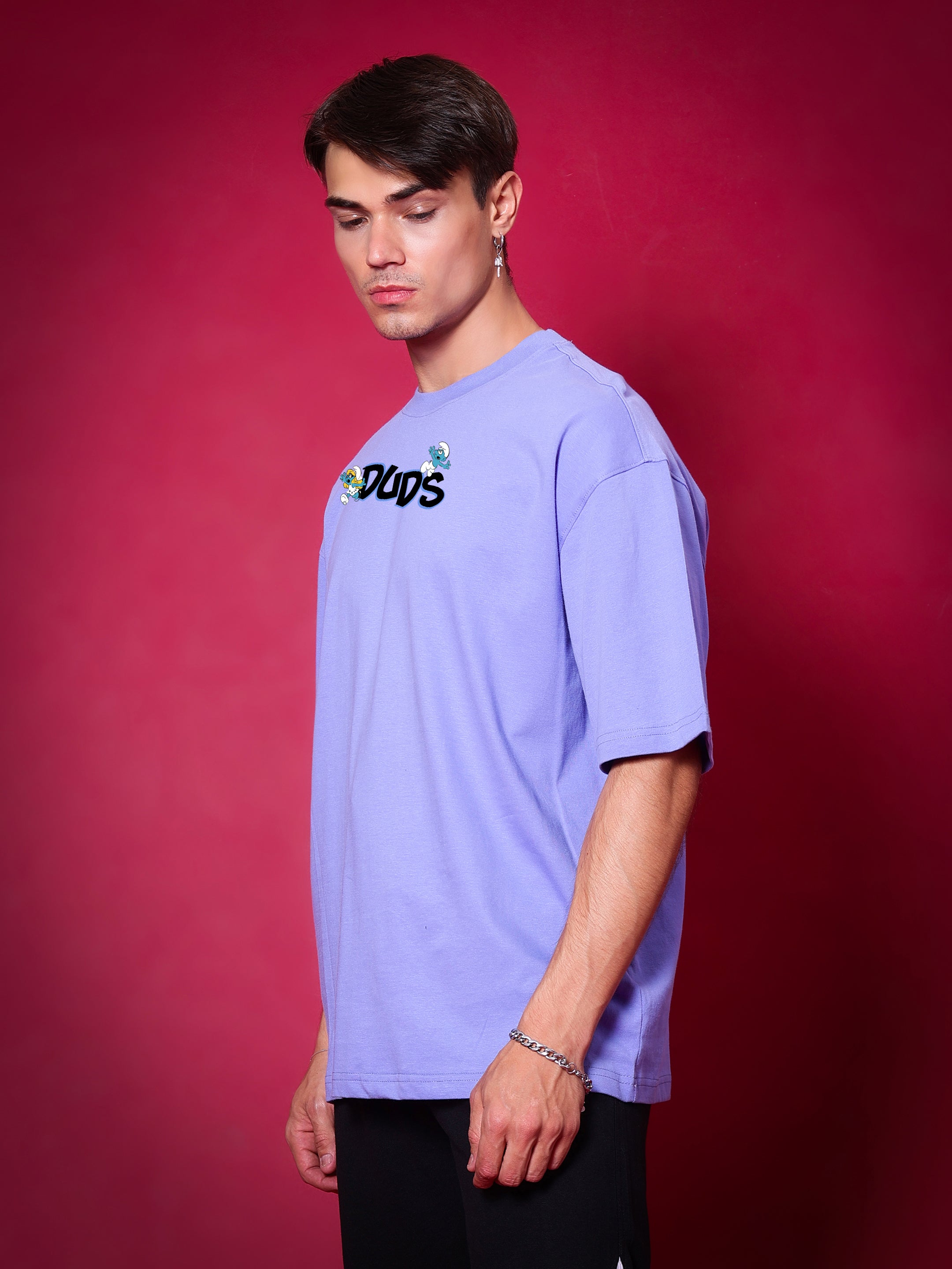 Model wearing SMURFS OVER-SIZED T-SHIRT PURPLE from DUDS against a red background.