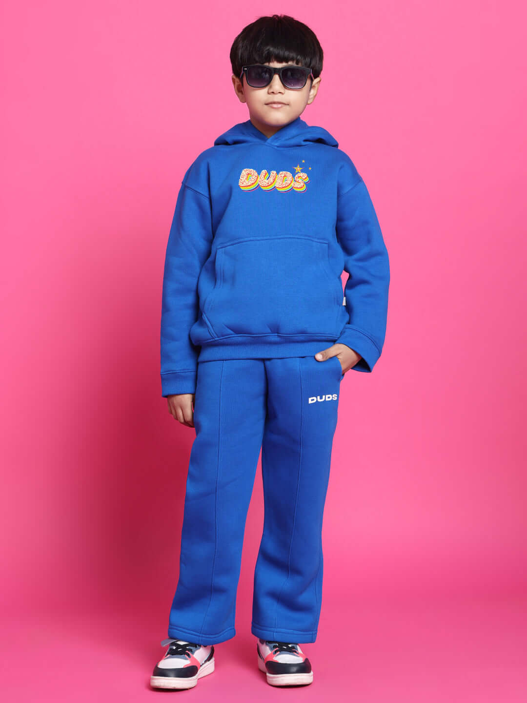 Child wearing blue Born to Shine co-ord outfit for boys and girls, featuring a hoodie and pants, styled with sunglasses.