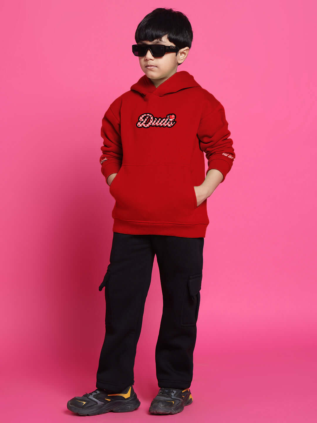 Boy wearing a red Cupcake Co-ord hoodie for boys and girls, featuring a comfortable fit, stands against a pink background