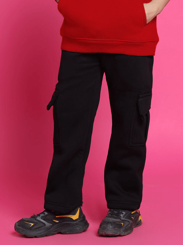 Child wearing red shirt and black cargo pants, standing on pink background, showcasing a stylish co-ord outfit for boys and girls.