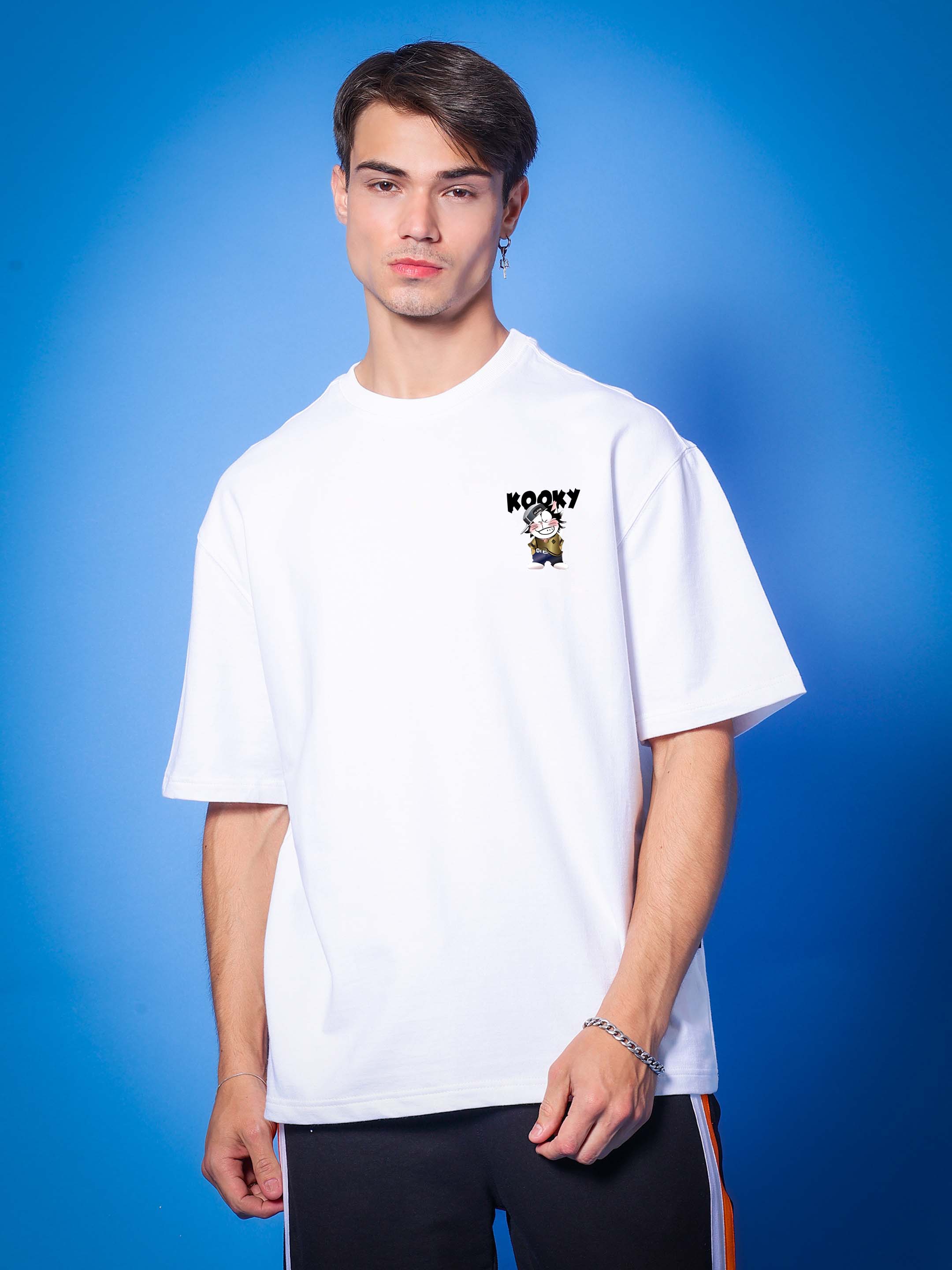 Model wearing KOOKY OVER-SIZED T-SHIRT WHITE made of premium cotton French terry and elastane on a blue background.