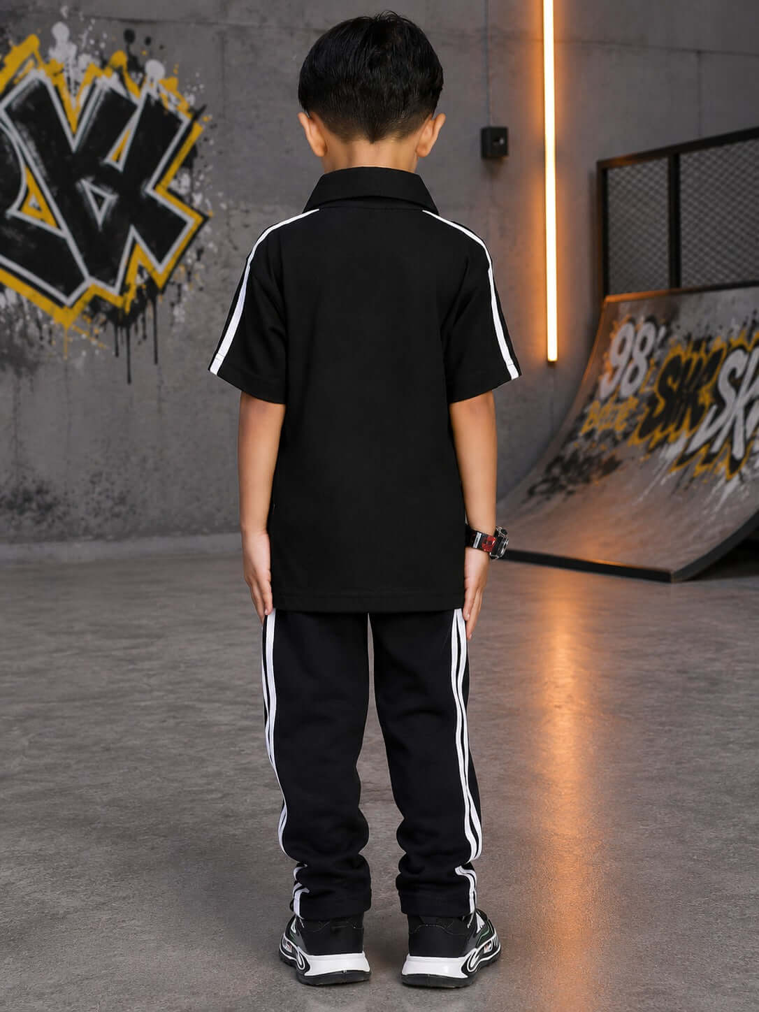 Boy wearing CHAMPION TRACK POLO CO-ORD FOR BOYS GIRLS BLACK from the back, showcasing sporty style and sleek design.