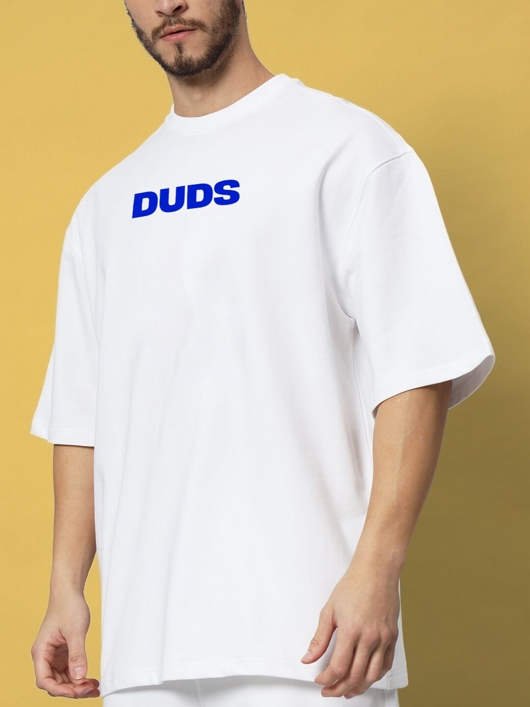Man wearing white T-shirt with blue 'DUDS' text on front, yellow background