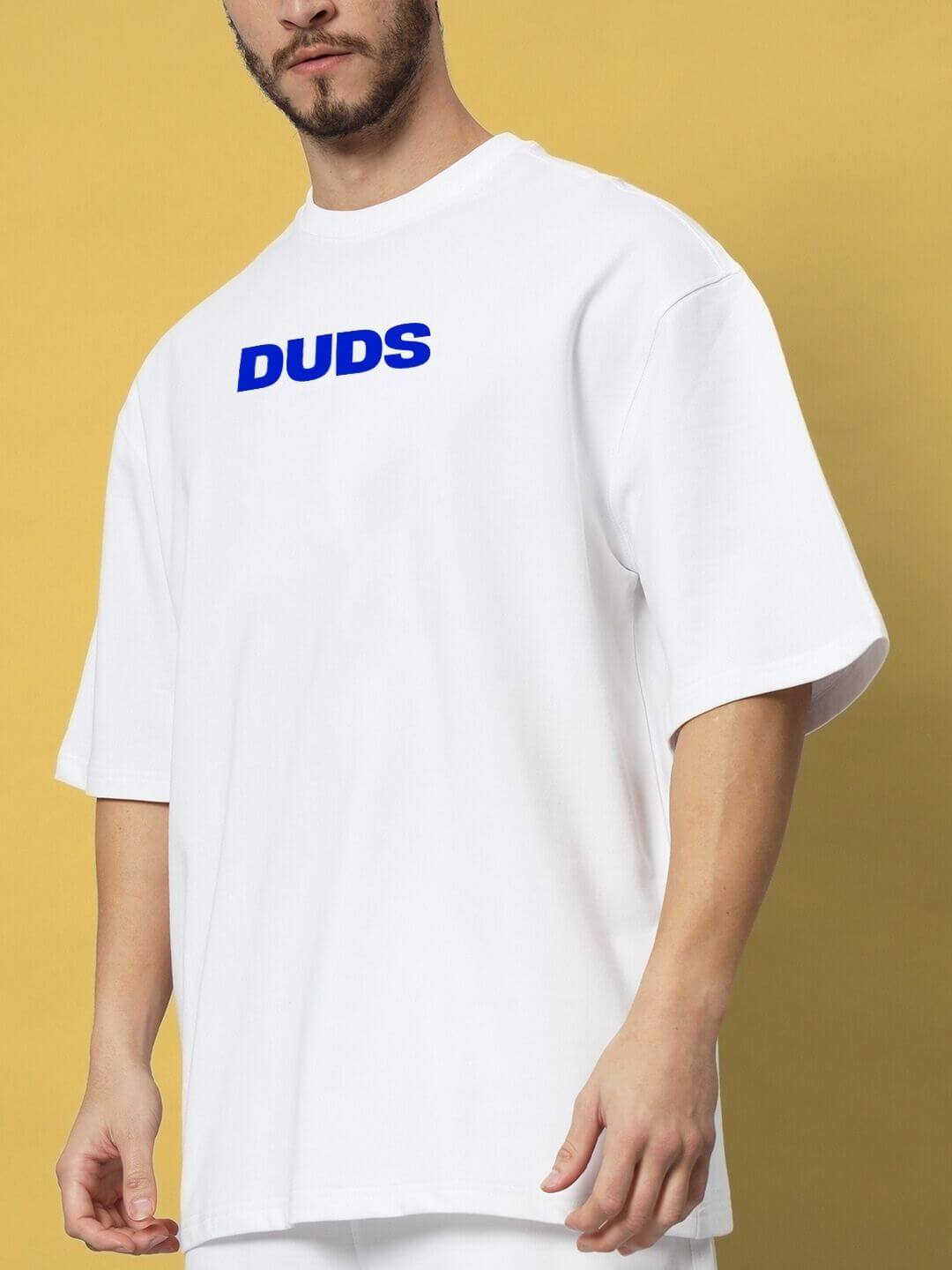 Model wearing ABSENT PRESENT CO-ORD SET WHITE, featuring a white oversized t-shirt with blue 'DUDS' logo on front.
