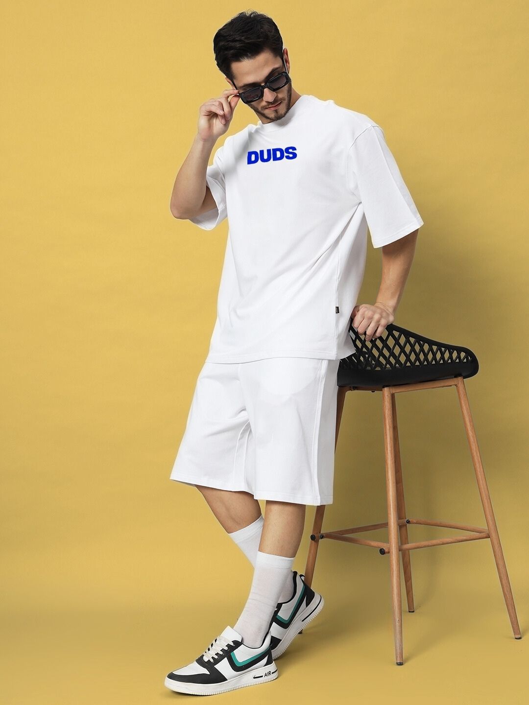 Man wearing white ABSENT PRESENT CO-ORD SET WHITE with relaxed silhouette, standing casually against a yellow background.