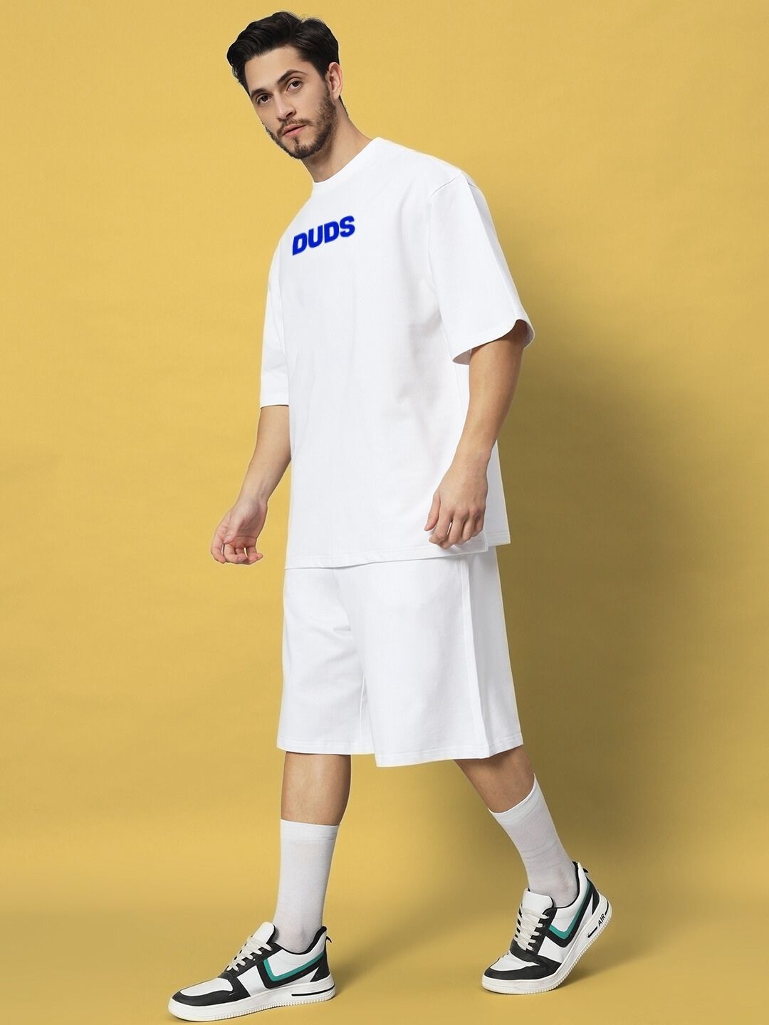 Man wearing ABSENT PRESENT CO-ORD SET WHITE on a beige background, showcasing modern minimalism and casual elegance.