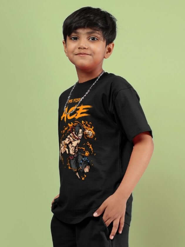 Boy wearing ACE T-SHIRT FOR BOYS AND GIRLS BLACK with graphic design on front, standing against a green background.