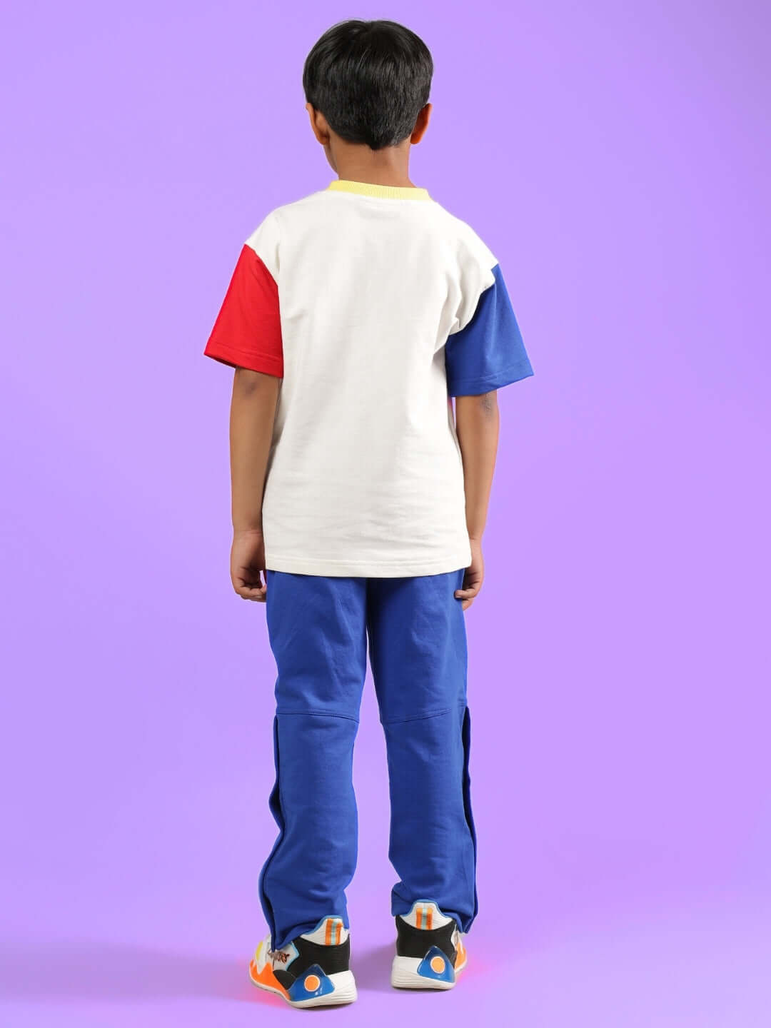 Child wearing Adonis Co-ord in off white and royal blue with red sleeves, showcasing the outfit's stylish design against a purple background.