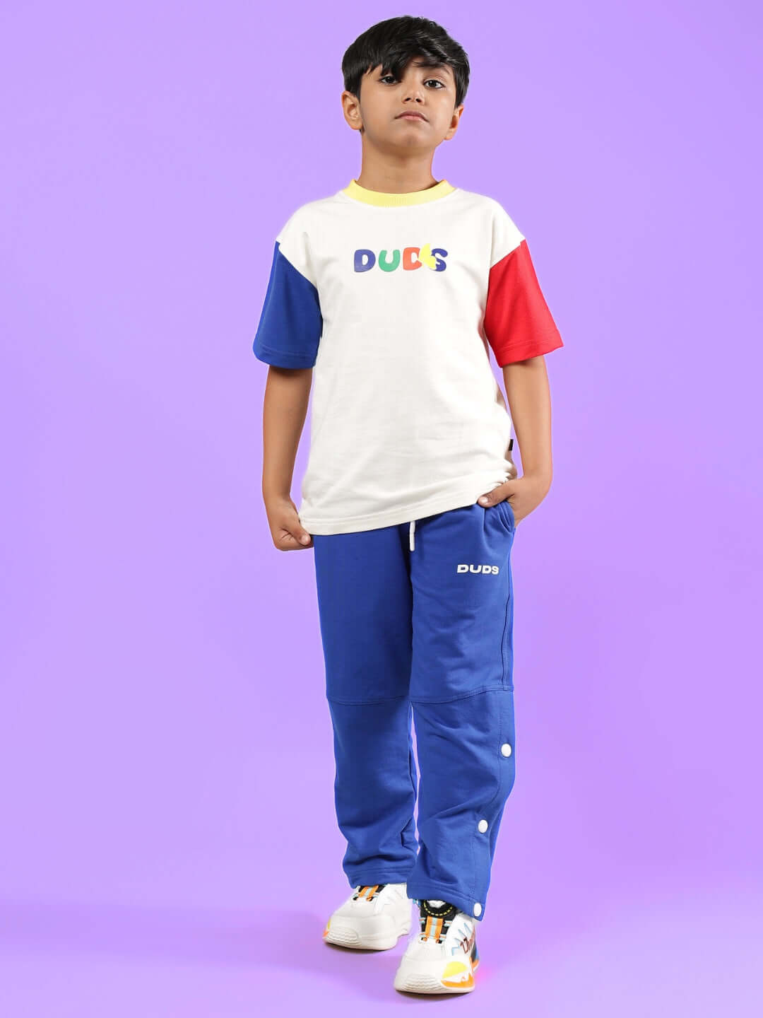 Child wearing Adonis Co-ord set in off white and royal blue, showcasing colorful design by DUDS against a purple background.