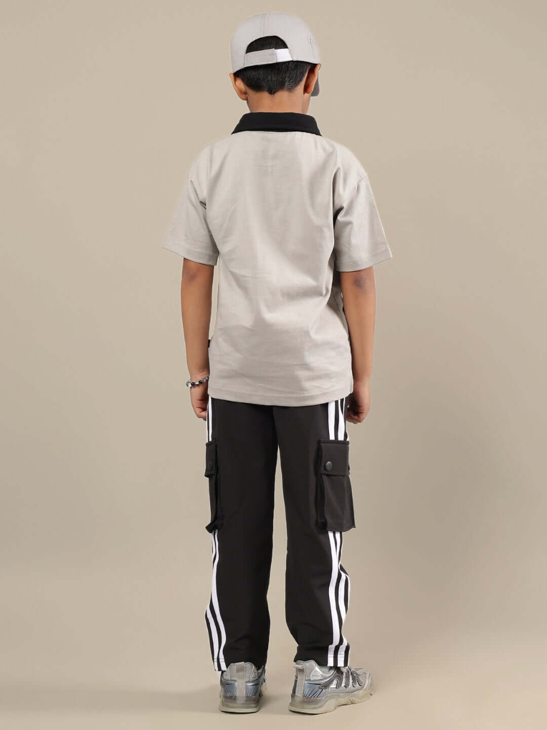 Child wearing grey and black co-ord set, including striped pants and cap, designed for boys and girls, highlighting casual style.