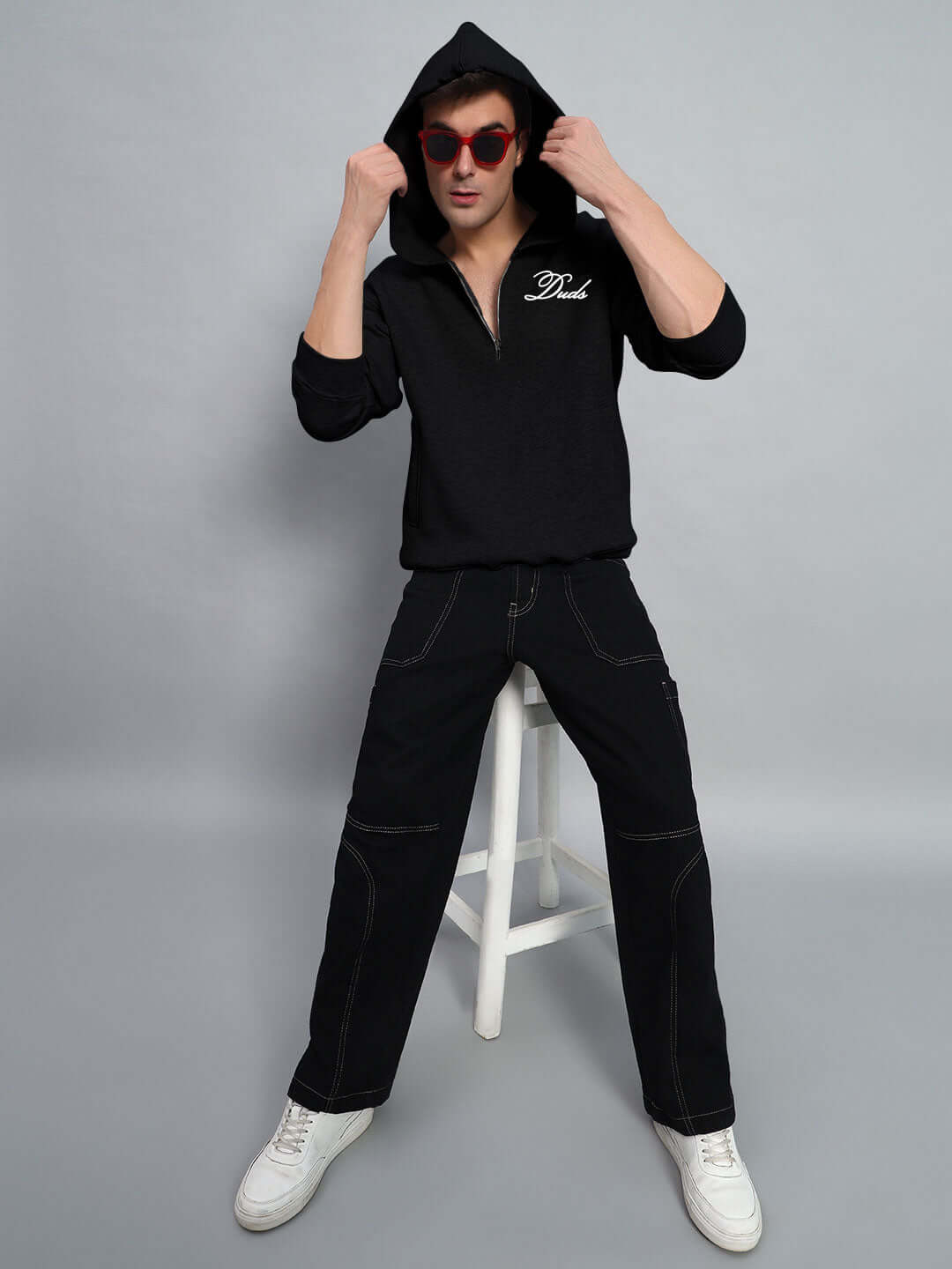 Model wearing WEARDUDS AMARILLO FLEECE HOODIE BLACK sitting on a stool, showcasing the comfortable and stylish fit.