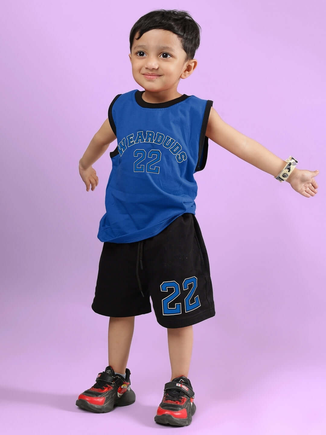 Child wearing AMIGA CO-ORD FOR BOYS & GIRLS BLUE BLACK, featuring sporty blue top and black shorts on a vibrant background.