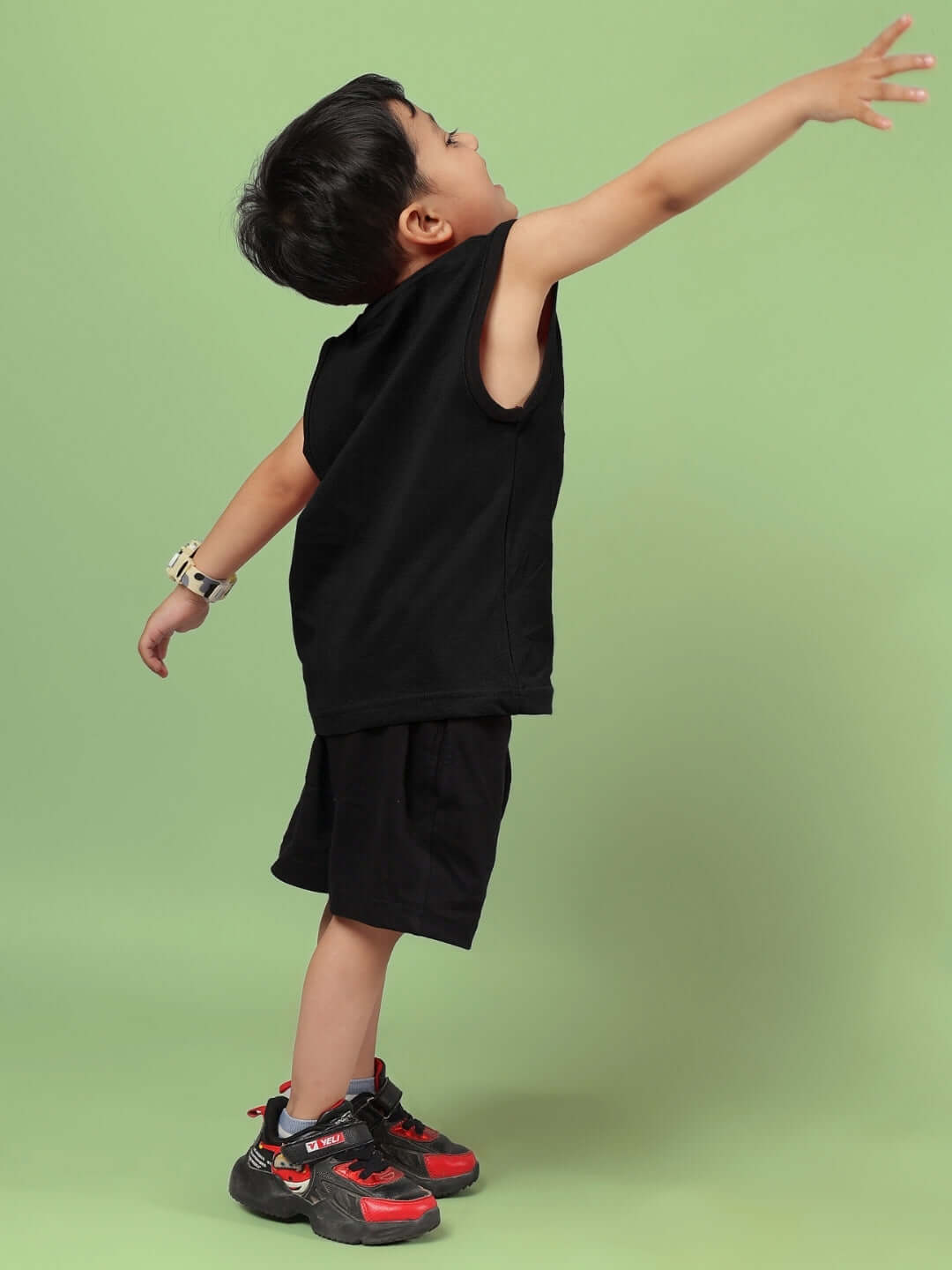 Child wearing AMIGA CO-ORD FOR BOYS & GIRLS BLACK outfit, striking a playful pose against a green background. Perfect for custom fit orders.