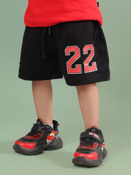 AMIGA SHORTS FOR BOYS & GIRLS BLACK RED with number 22 design, shown on child wearing red and black sneakers.