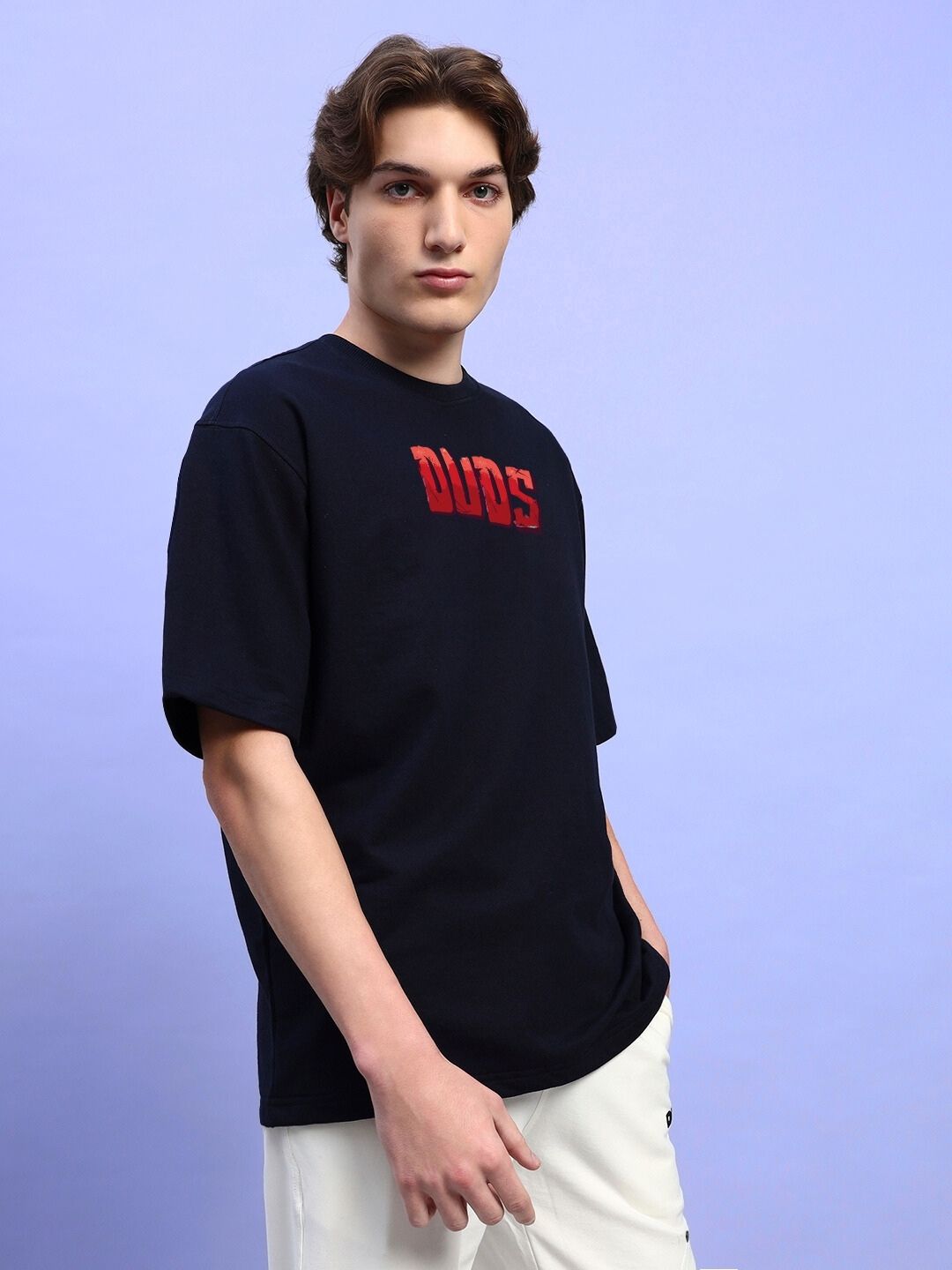 Model wearing AMPERES PRINT OVERSIZED T-SHIRT BLACK with red lettering on front, posing against a light blue background.