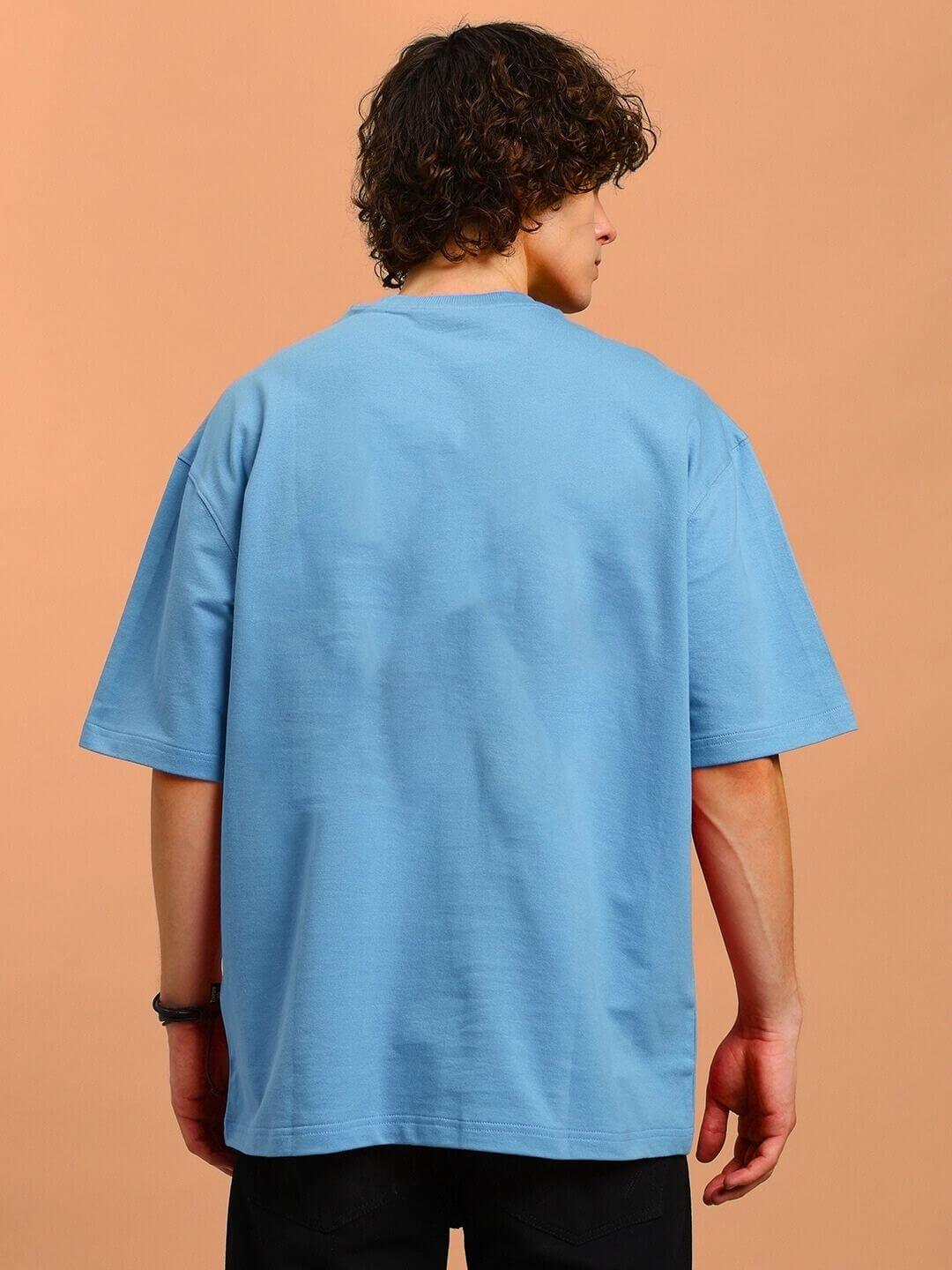 Back view of ANGRY SNAKE WD PRINTED OVERSIZED T-SHIRT LIGHT BLUE on model against a peach background.