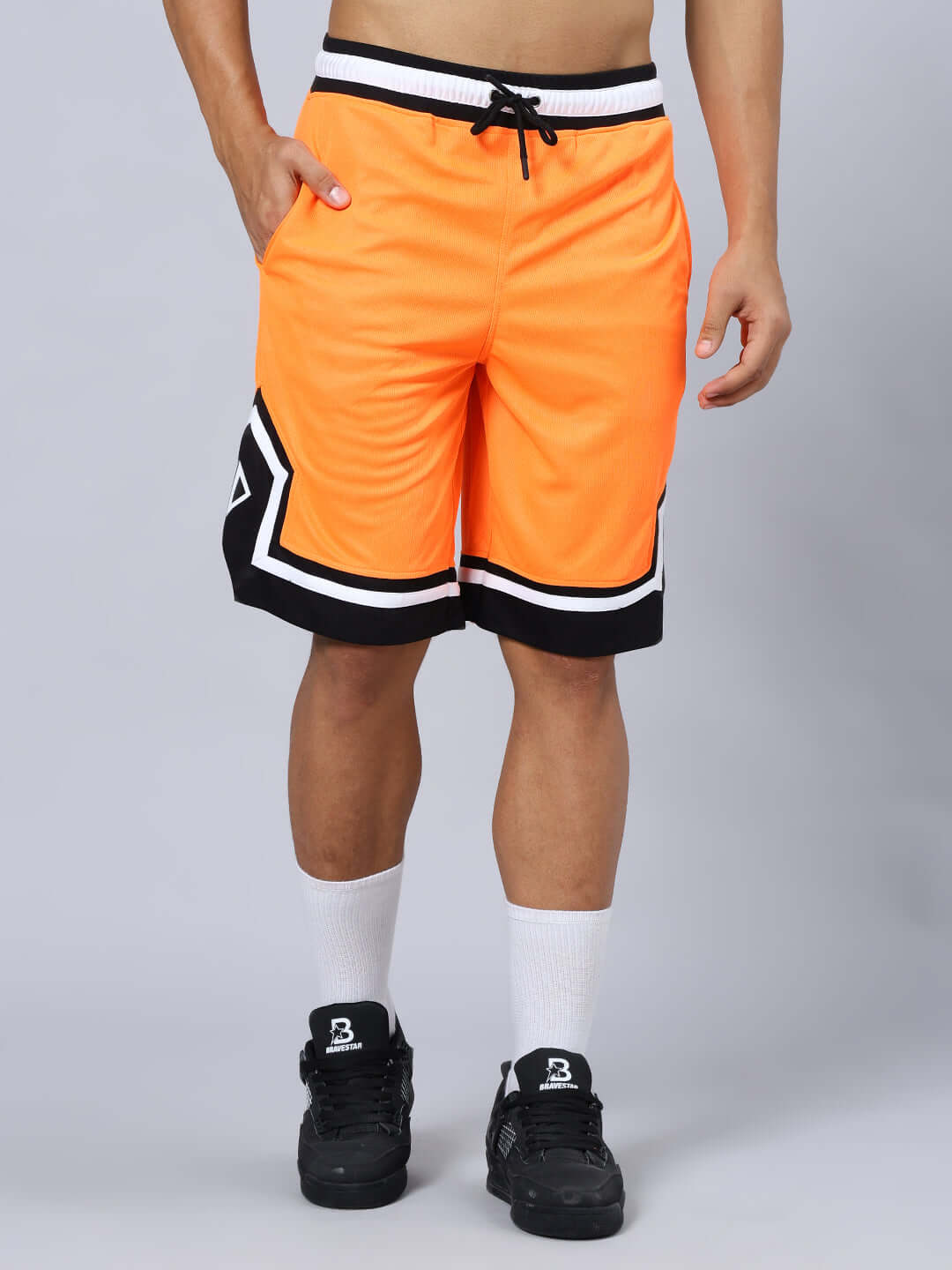 ARMADO REGULAR FIT SHORTS ORANGE BLACK Man wearing ARMADO Regular Fit Shorts in orange and black with white socks and black sneakers.