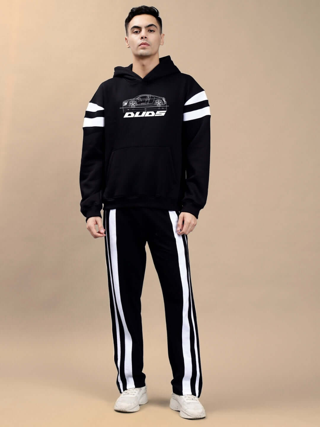 Man wearing AUDI R8 FLEECE COLORBLOCK OVERSIZE HOODIE BLACK with sporty design, showcasing Gen-Z fashion trend on beige background.