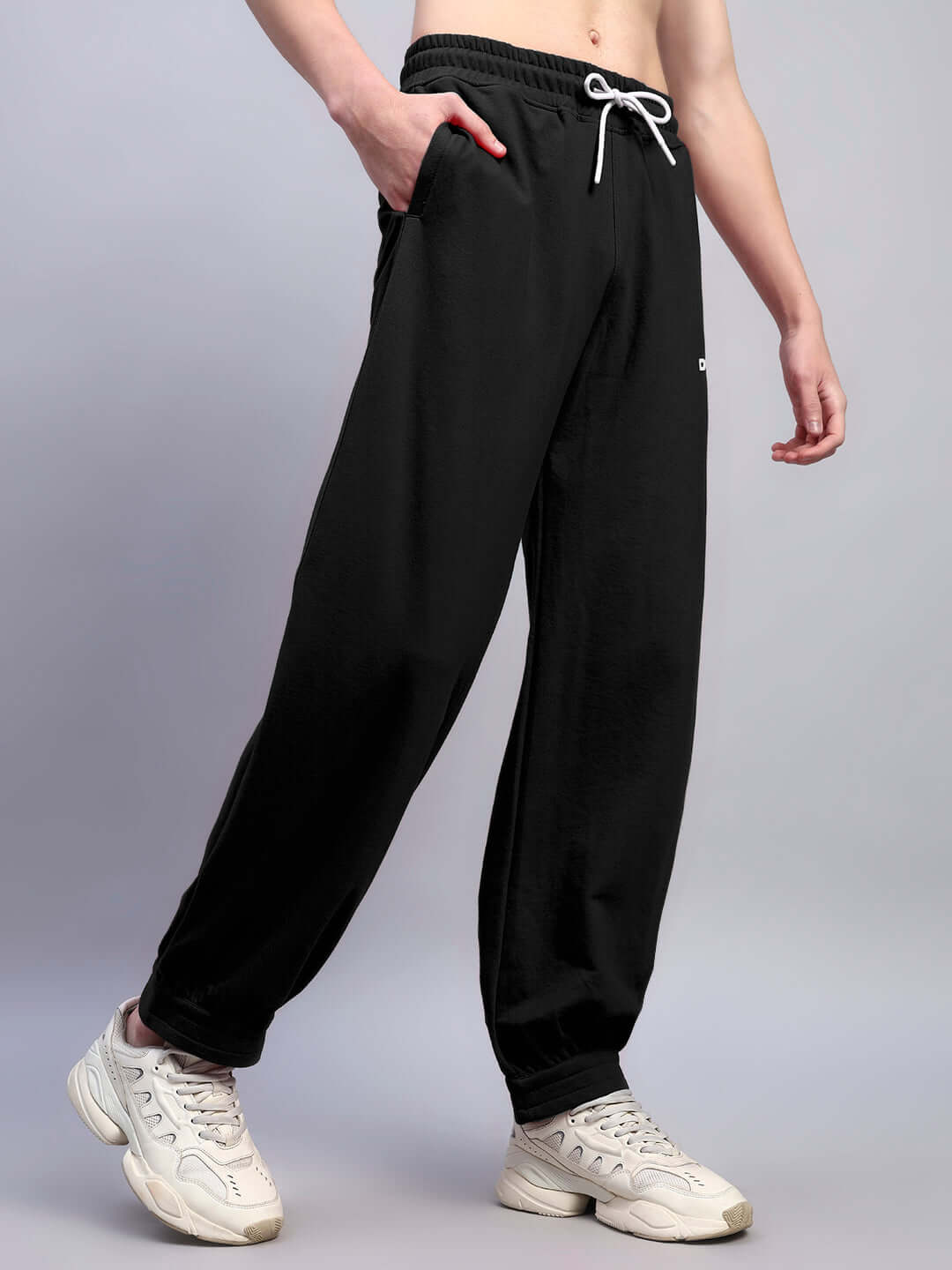 Man wearing AUSTRIAN RELAXED-FIT JOGGERS BLACK with white sneakers, showcasing a minimalist streetwear look.