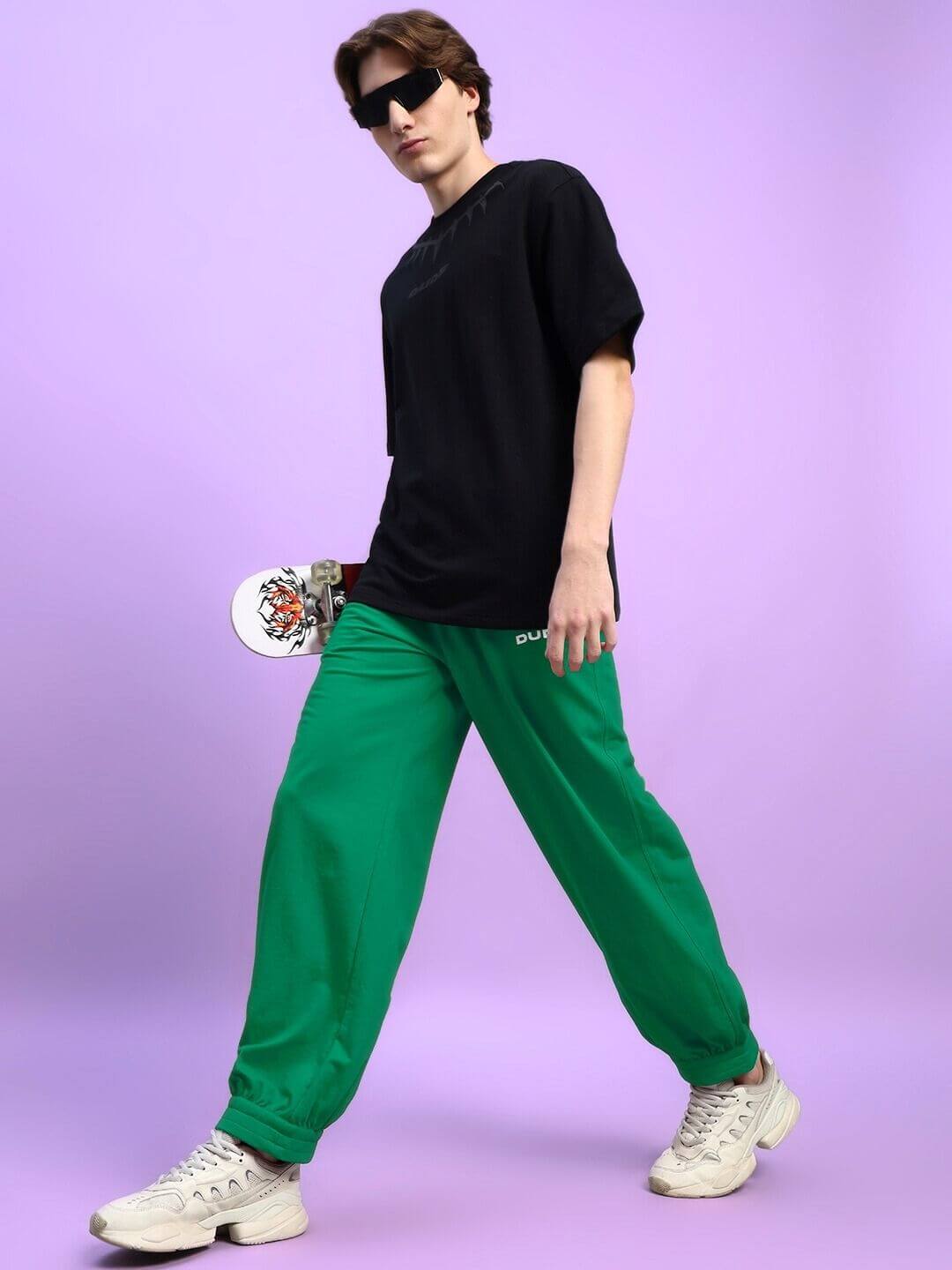Stylish model wearing Austrian Relaxed-Fit Joggers Green with a skateboard, showcasing trendy streetwear fashion.
