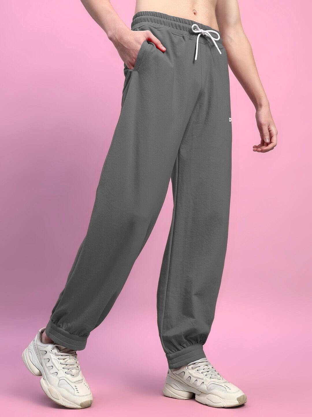 Person wearing AUSTRIAN RELAXED-FIT JOGGERS GREY, showcasing modern street style and comfort on a pink background.