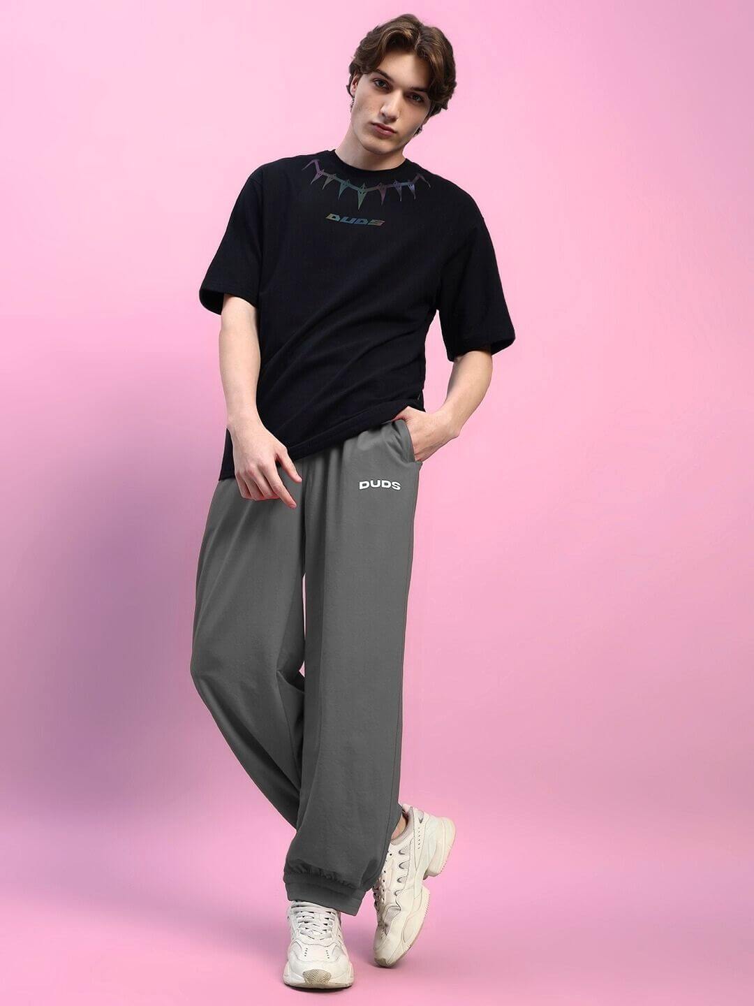 Model wearing AUSTRIAN RELAXED-FIT JOGGERS GREY styled with a casual black t-shirt, showcasing modern streetwear fashion.