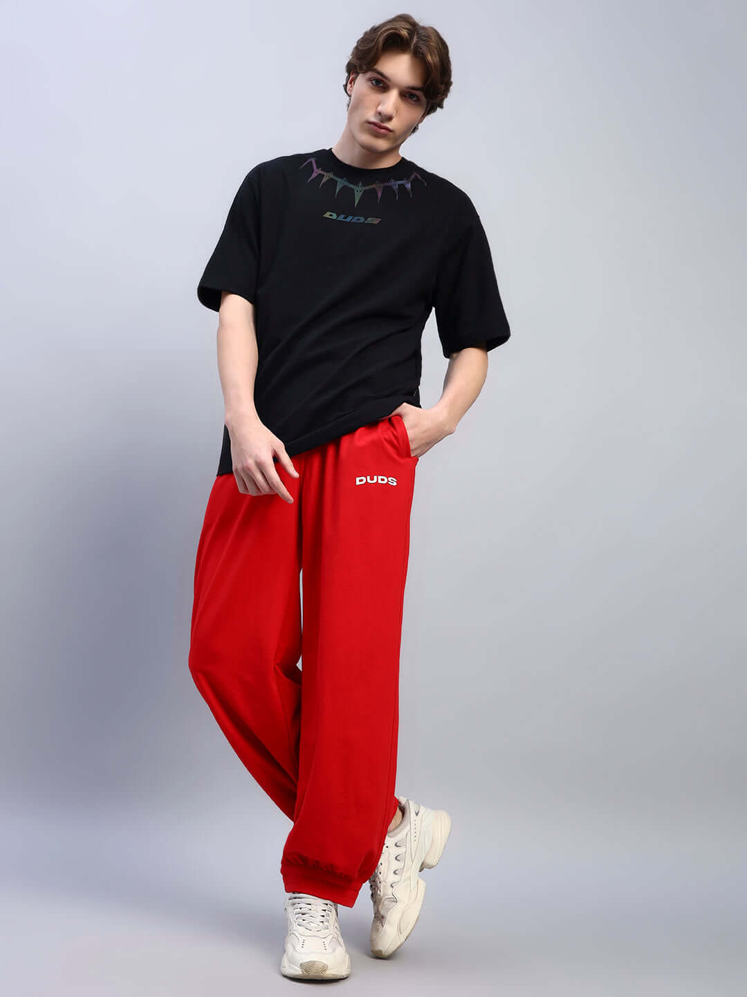 Model wearing AUSTRIAN RELAXED-FIT JOGGERS RED with black t-shirt and white sneakers, showcasing vibrant red color and relaxed-fit style.