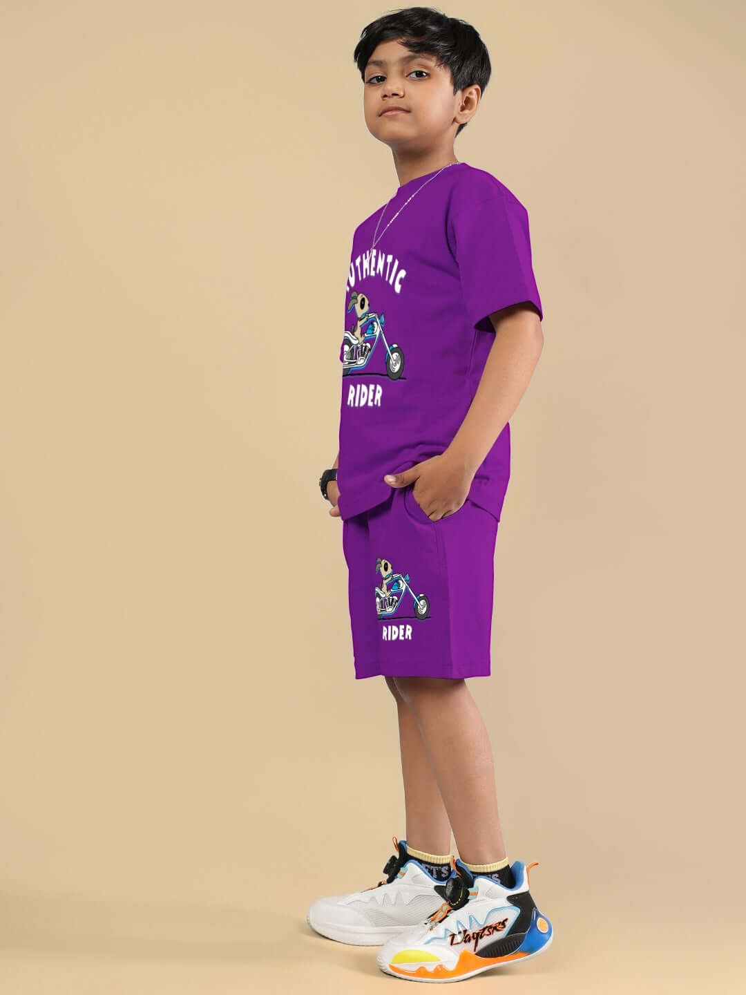 Child wearing AUTHENTIC RIDER CO-ORD FOR BOYS & GIRLS PURPLE set, featuring purple t-shirt and shorts, standing with hands in pockets.