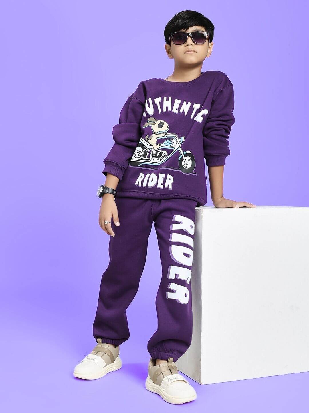 Child wearing AUTHENTIC RIDER FLEECE CO-ORD FOR BOYS AND GIRLS PURPLE, posing against a light purple background, showcasing casual style.