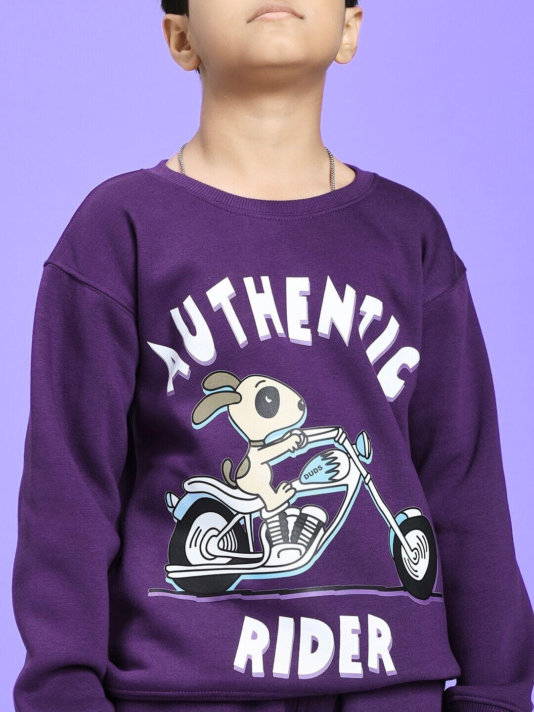 Child wearing AUTHENTIC RIDER FLEECE SWEATSHIRT FOR BOYS AND GIRLS PURPLE with cartoon bike graphic.