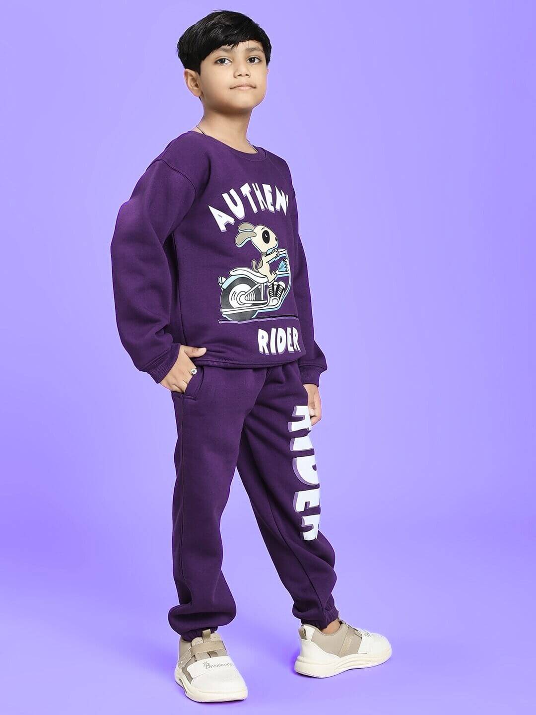 Boy wearing AUTHENTIC RIDER FLEECE CO-ORD FOR BOYS AND GIRLS PURPLE, displaying a bold graphic on a matching sweatshirt and sweatpants.