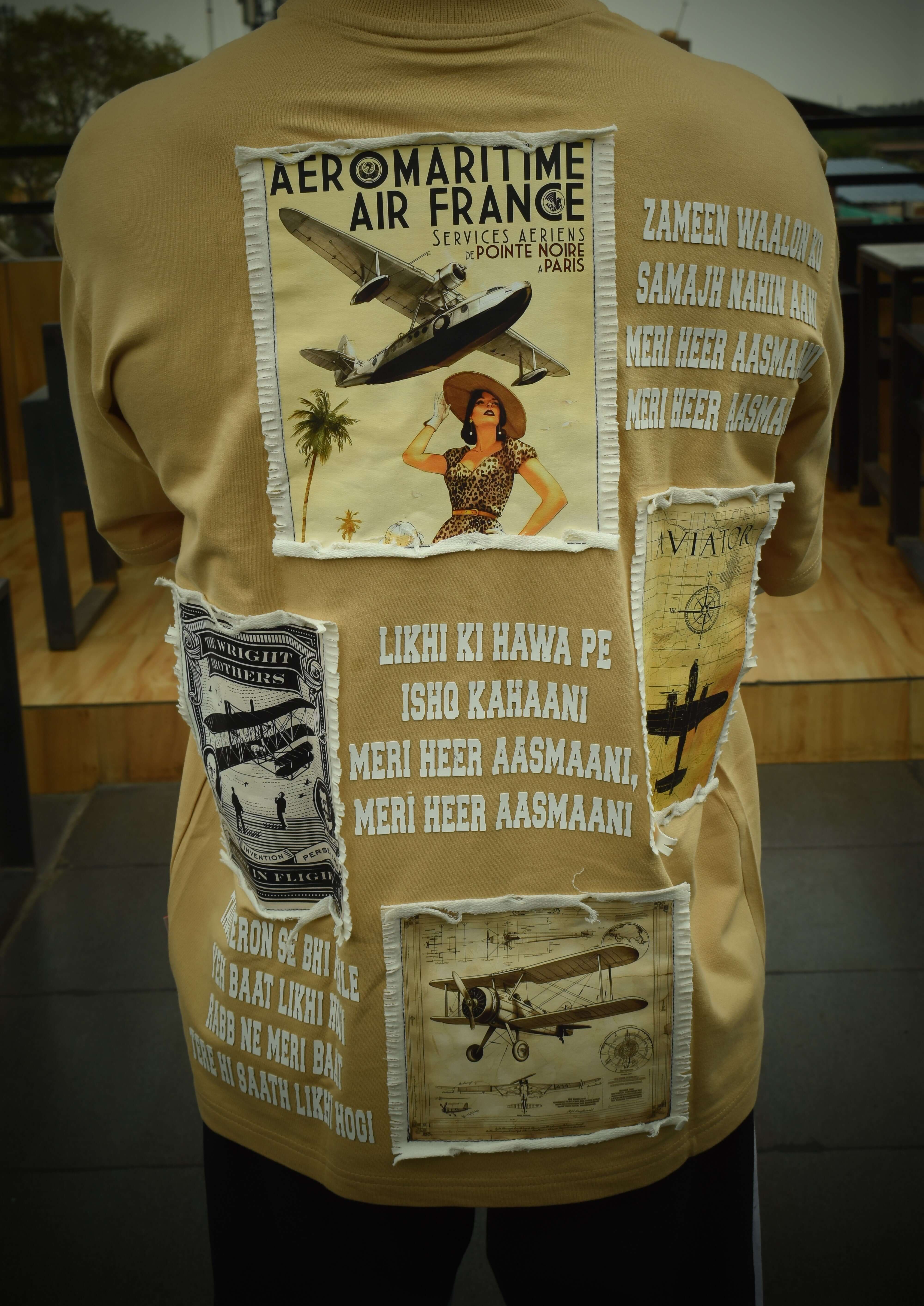 Back view of beige oversized t-shirt featuring vintage poster designs and typography, made from premium cotton fabric.