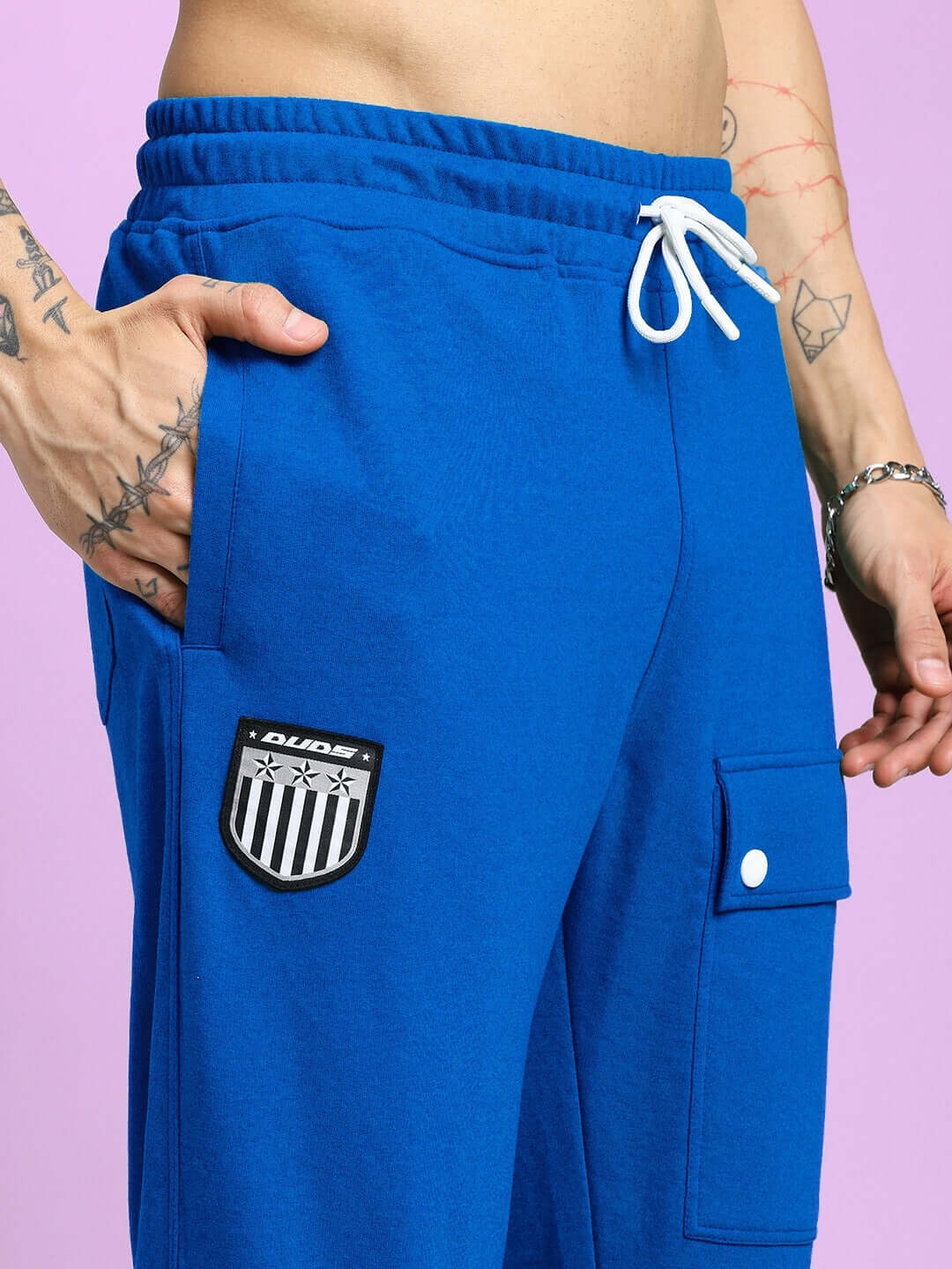 Person wearing AWESOME FLAP POCKET BAGGY JOGGER BLUE with utility pocket and logo patch, showcasing streetwear style.