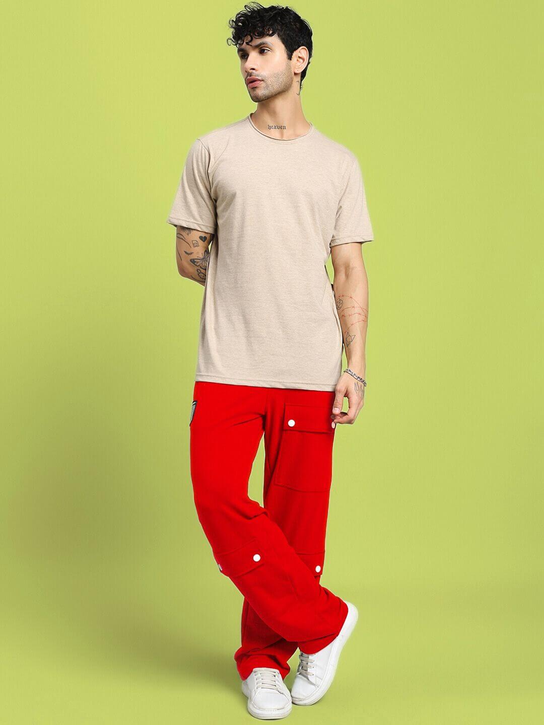 Male model wearing AWESOME FLAP POCKET BAGGY JOGGER RED with a neutral t-shirt and white sneakers, standing against a light green background.