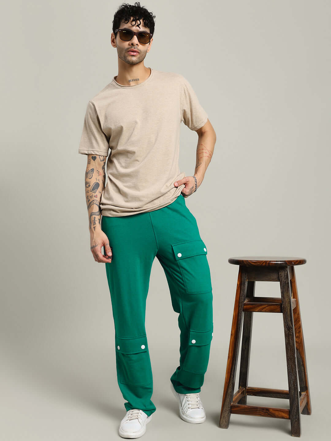 Model wearing AWESOME FLAP POCKET BAGGY JOGGER GREEN with beige t-shirt and sunglasses, showcasing casual urban fashion style.