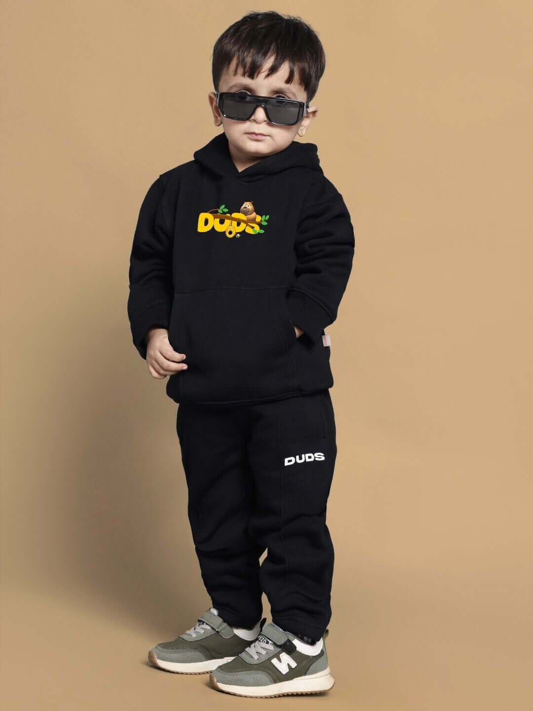 Child wearing Bablu Dablu black co-ord set from Duds with logo, standing stylishly in sunglasses.