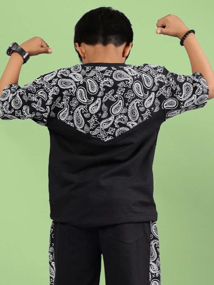 BALADEER OVERSIZED T-SHIRT FOR BOYS & GIRLS BLACK with paisley pattern, rear view, worn by child flexing arms, showcasing durable fabric design.