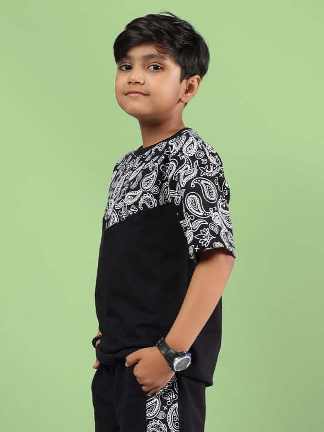 Boy wearing BALADEER OVERSIZED T-SHIRT FOR BOYS & GIRLS BLACK with paisley design on green background