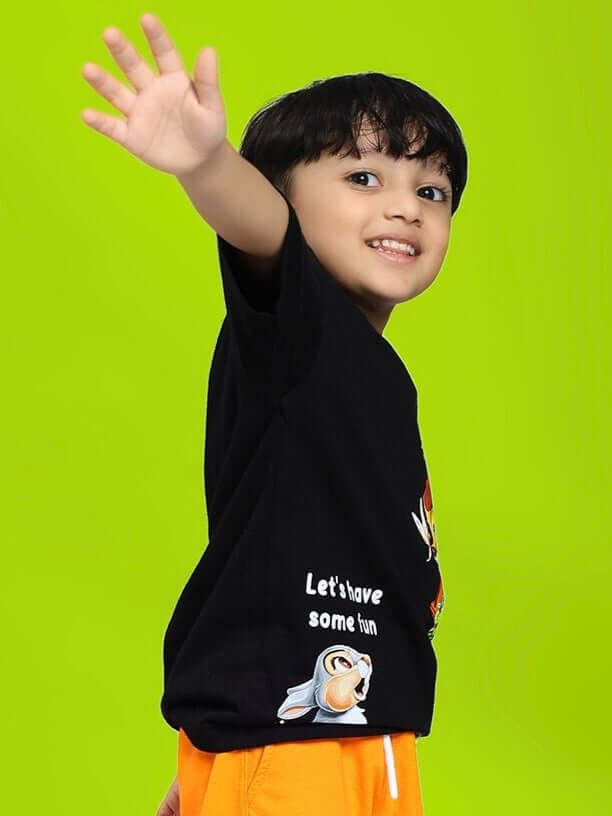 Boy wearing BAMBI TOON T-SHIRT FOR BOYS AND GIRLS BLACK with playful Bambi and Thumper design on neon green background.