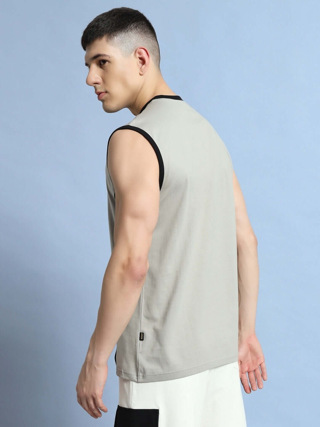 Man wearing a grey BARE ARMS gym t-shirt, side view, showcasing the sleeveless design and comfortable fit for active wear.