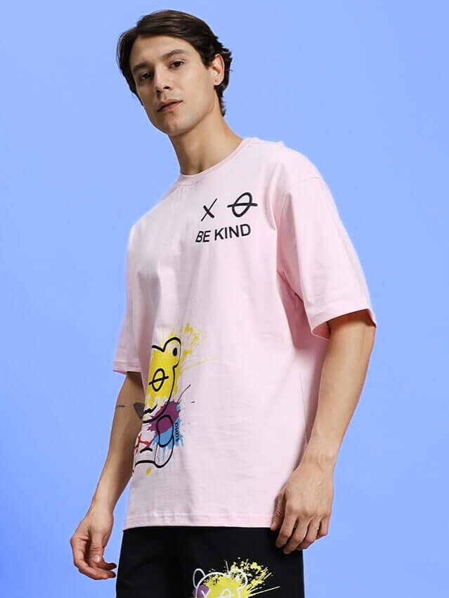 Model wearing BE KIND OVER-SIZED T-SHIRT PINK with graphic design and text for a casual, stylish look